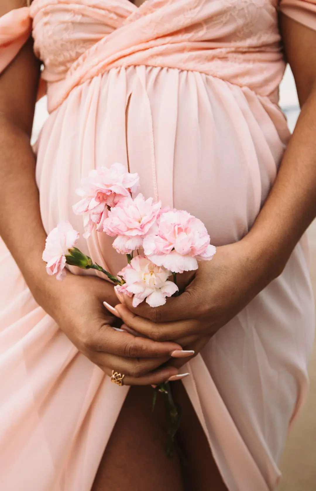 Photo by Evie Martinez A pregnant woman holding a bouquet of flowers